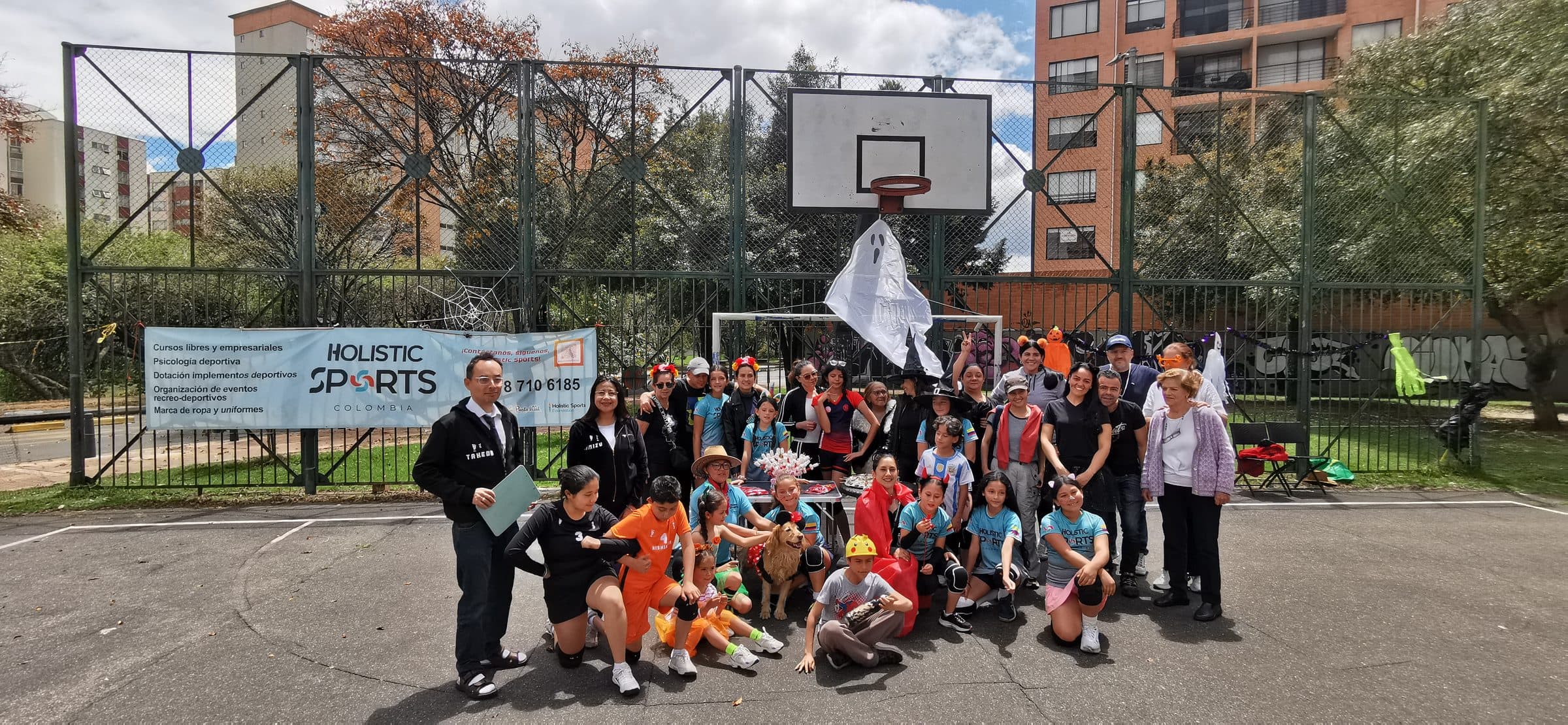 Niños, familias y equipo de HSC reunidos junto al pendón de Holistic Sports en una cancha de barrio